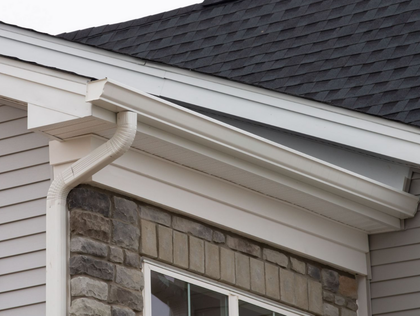 White gutters on a house with a gray roof and stone facade.