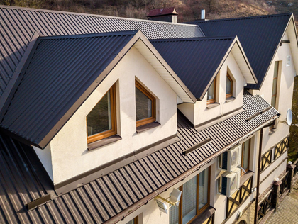 Dark gray corrugated metal roof with white gabled dormers and brown window frames.