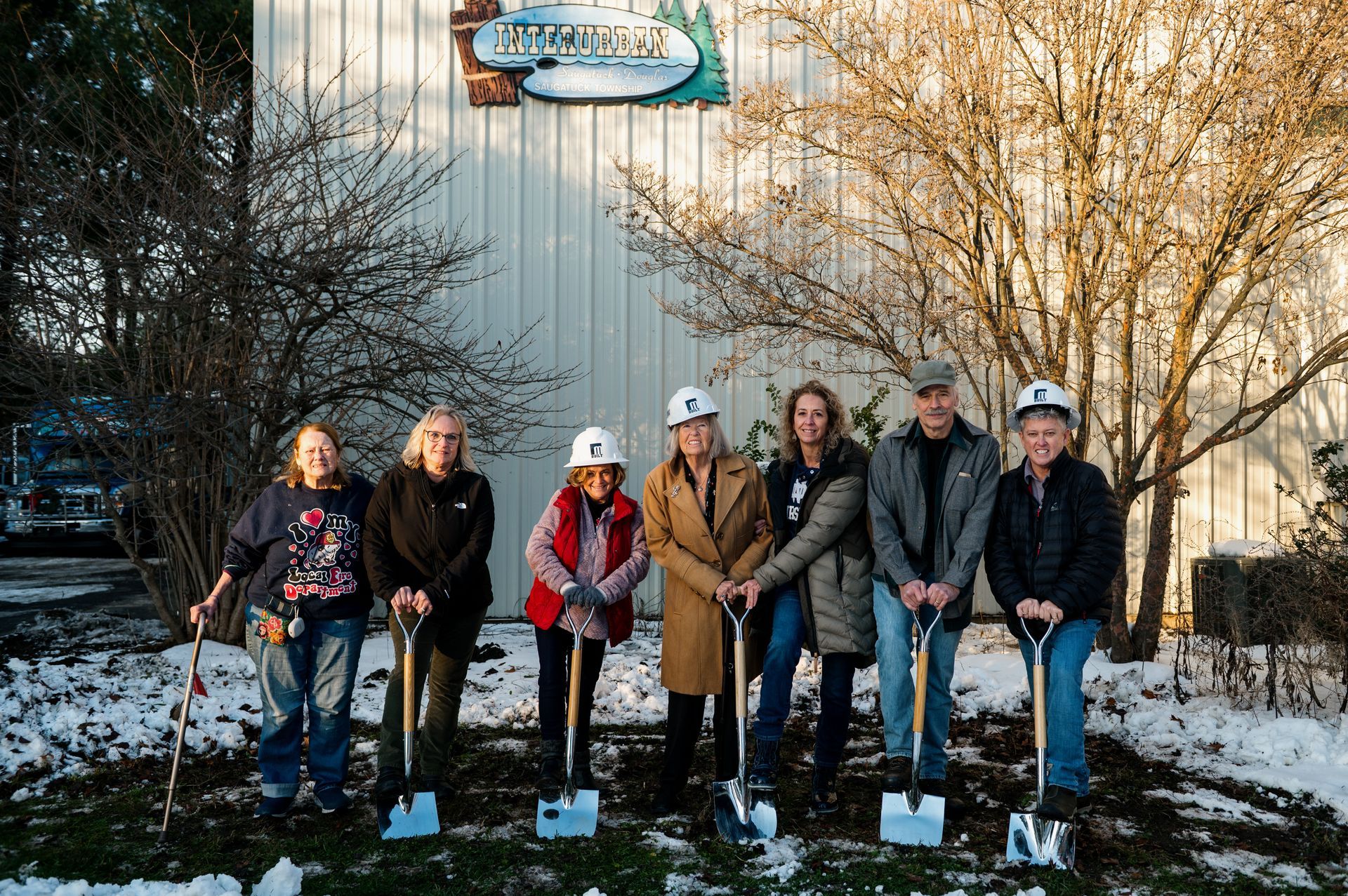 Members of the Interurban Board of Directors holding shovels standing in front of the headquarters building