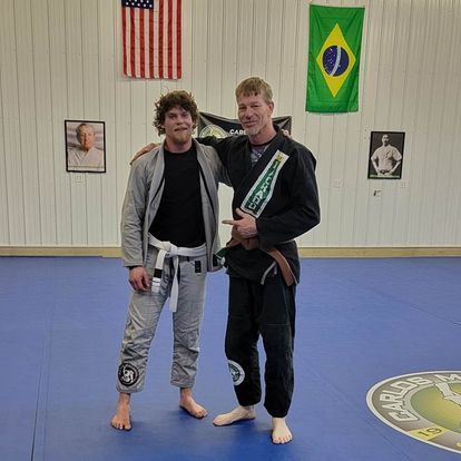 Two men are posing for a picture in a martial arts gym.