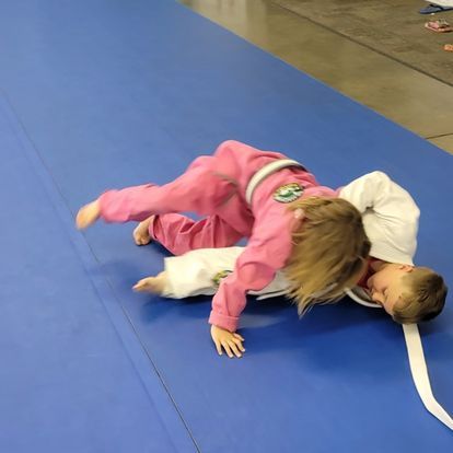 A boy and a girl are wrestling on a blue mat