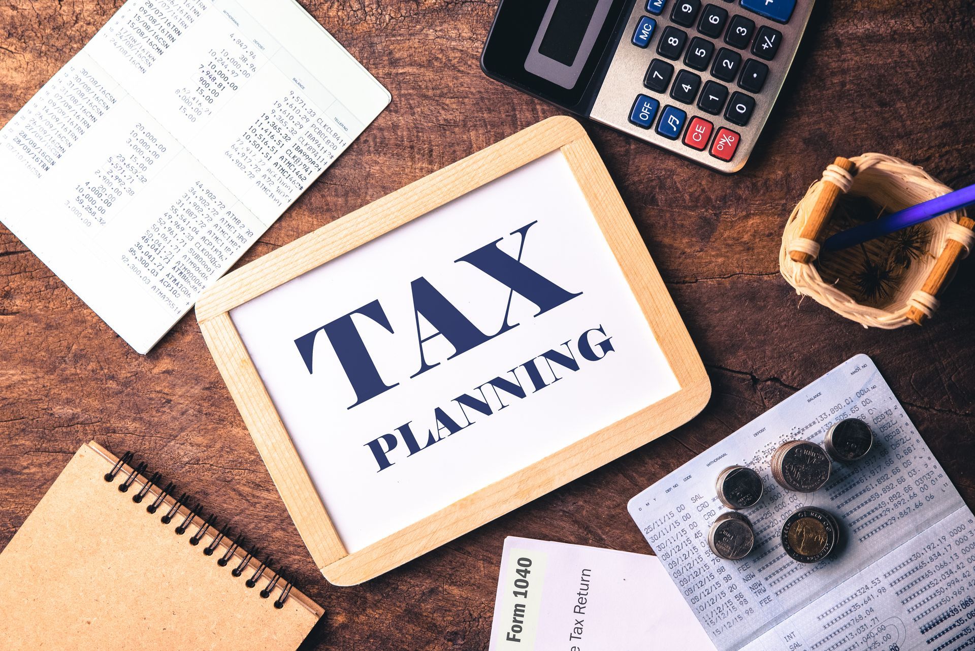 Tax planning sign on desk with calculator, receipts, coins, and notebook.