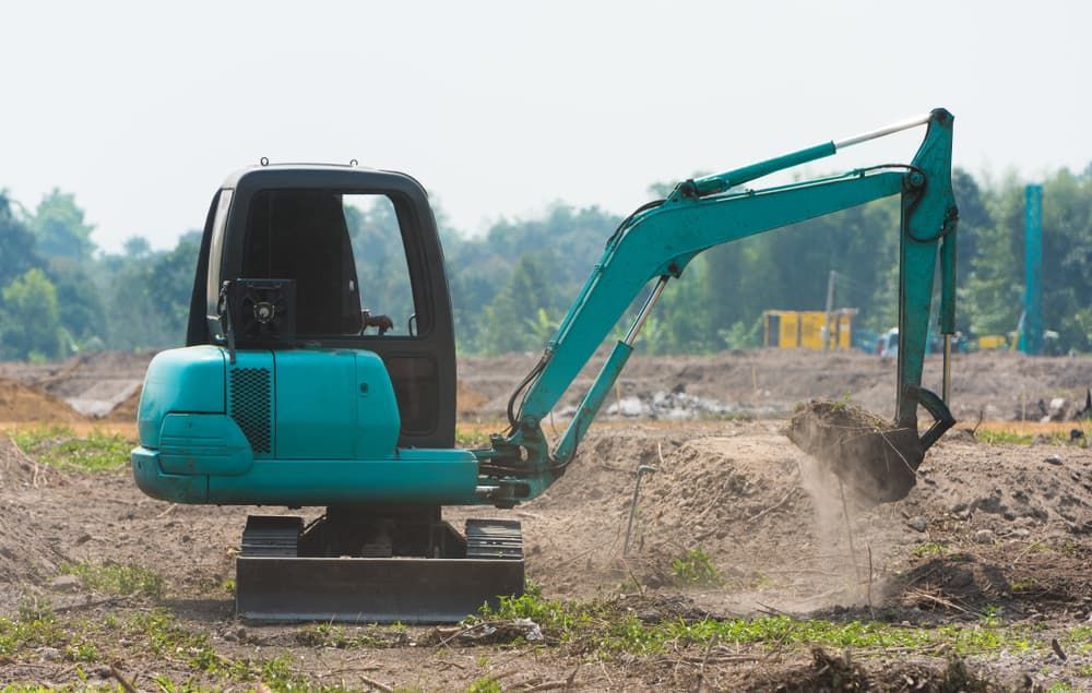 A Small Excavator Is Digging A Hole In A Dirt Field - Micro Excavations & Earthmoving in Burleigh Heads, QLD