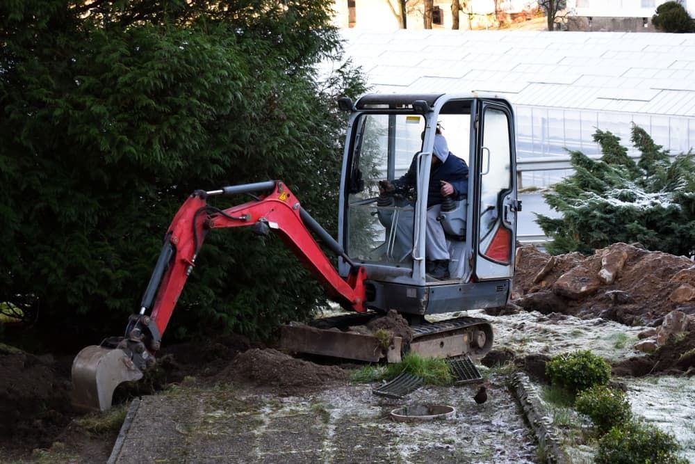A Man Is Driving A Small Excavator In A Garden - Micro Excavations & Earthmoving in Nerang, QLD