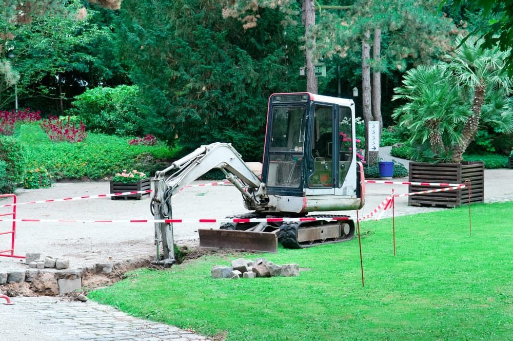 A Small Excavator Is Sitting On The Grass In A Park - Micro Excavations & Earthmoving in Helensvale, QLD