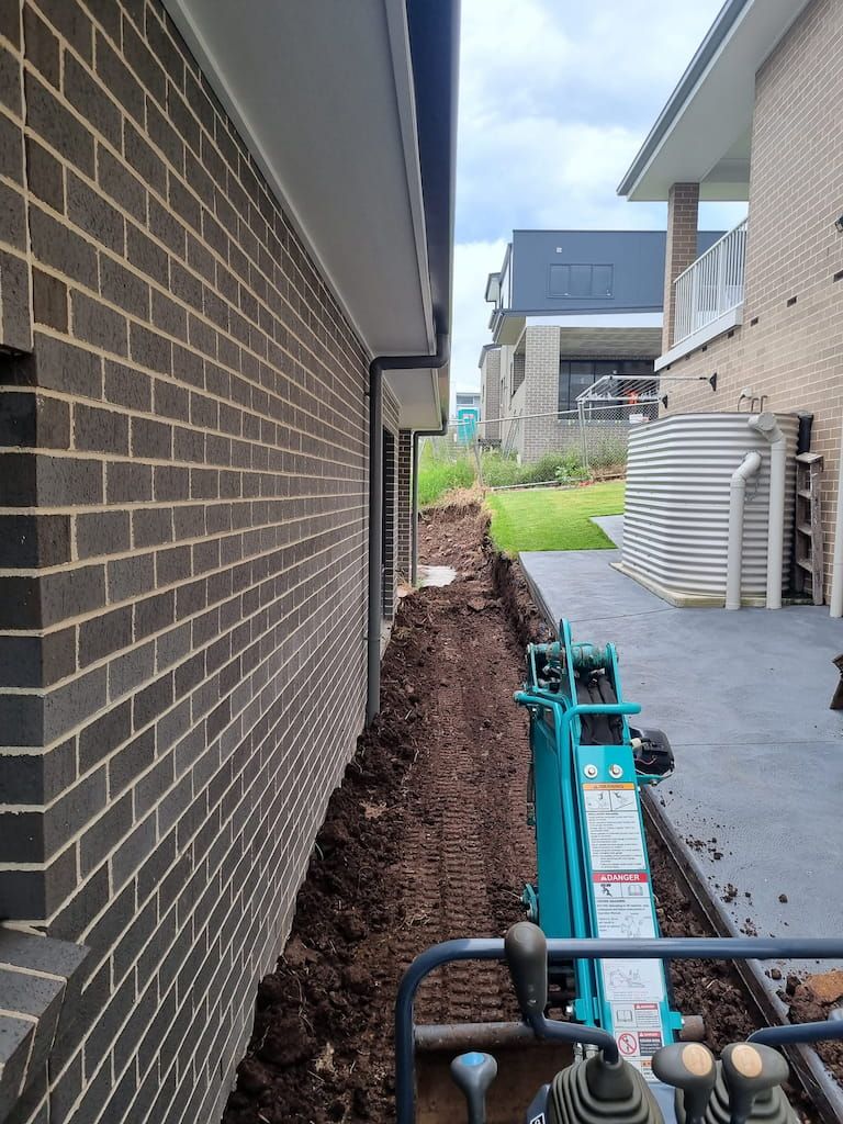 A Brick Wall Is Behind A Machine That Says ' Warning ' On It - Mini Earth Works & Excavation on the Gold Coast, QLD