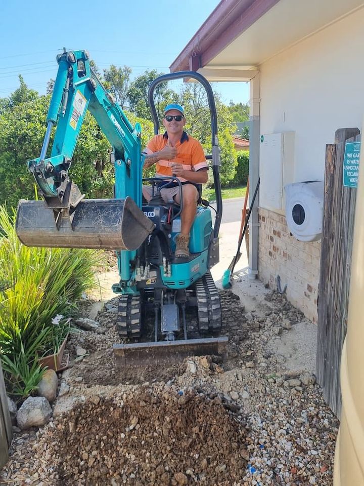 A Man Is Driving A Small Excavator In Front Of A House - Mini Earth Works & Excavation on the Gold Coast, QLD