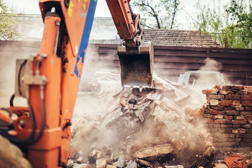 A Bulldozer Is Demolishing A Brick Building - Micro Excavations & Earthmoving in Southport, QLD