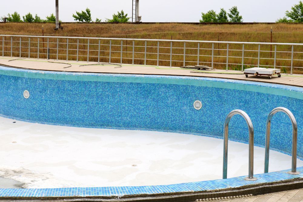 Empty Swimming Pool With Blue Tile Interior and Stainless Steel Handrails and Ladder — Bombs Away in Burleigh Heads, QLD