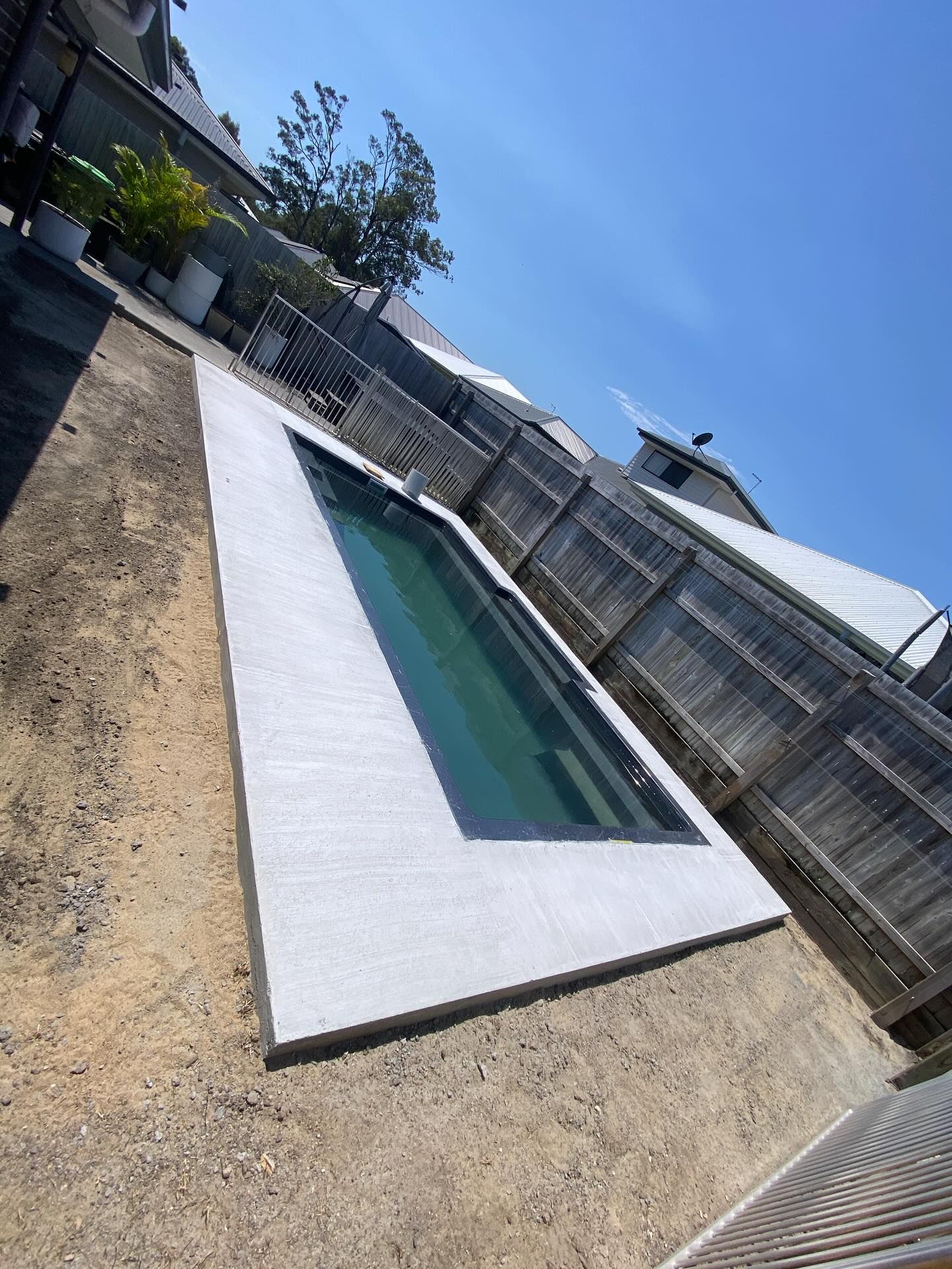 Rectangular Pool With Gray Trim Surrounded by Gravel and Wooden Fence Under Blue Sky — Bombs Away Pools in Coolangatta, QLD