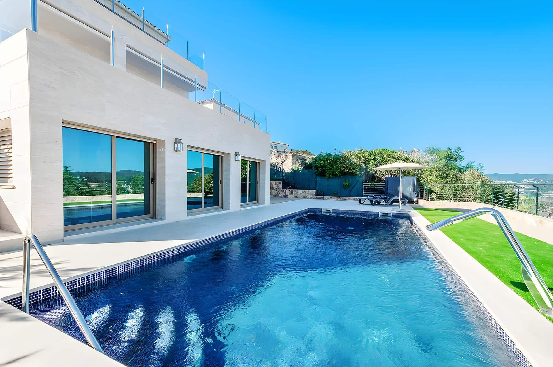 White Villa With a Blue-tiled Pool, Patio, and Lawn Under a Bright Blue Sky — Bombs Away Pools in Coolangatta, QLD