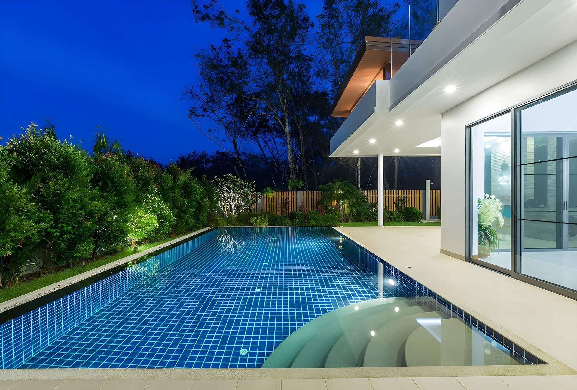 Luxury Home With a Lit Swimming Pool at Night. Blue Tiles, Glass Doors — Bombs Away Pools in Coolangatta, QLD