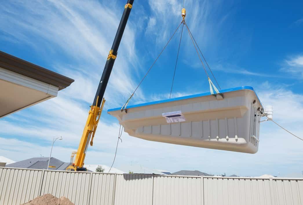 A Crane Lifting a Rectangular, Light-colored Pool Into a Backyard — Bombs Away Pools in Southport, QLD