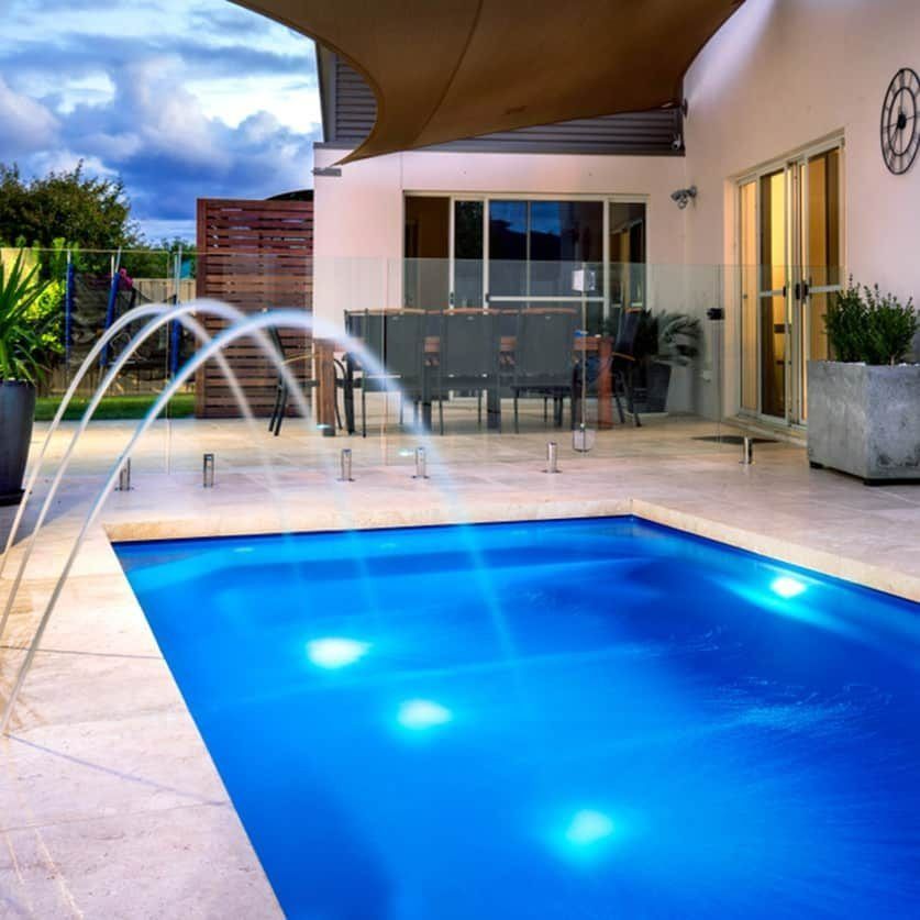 Pool With Water Fountains and Bright Blue Water, Patio With Furniture — Bombs Away Pools in Palm Beach, QLD