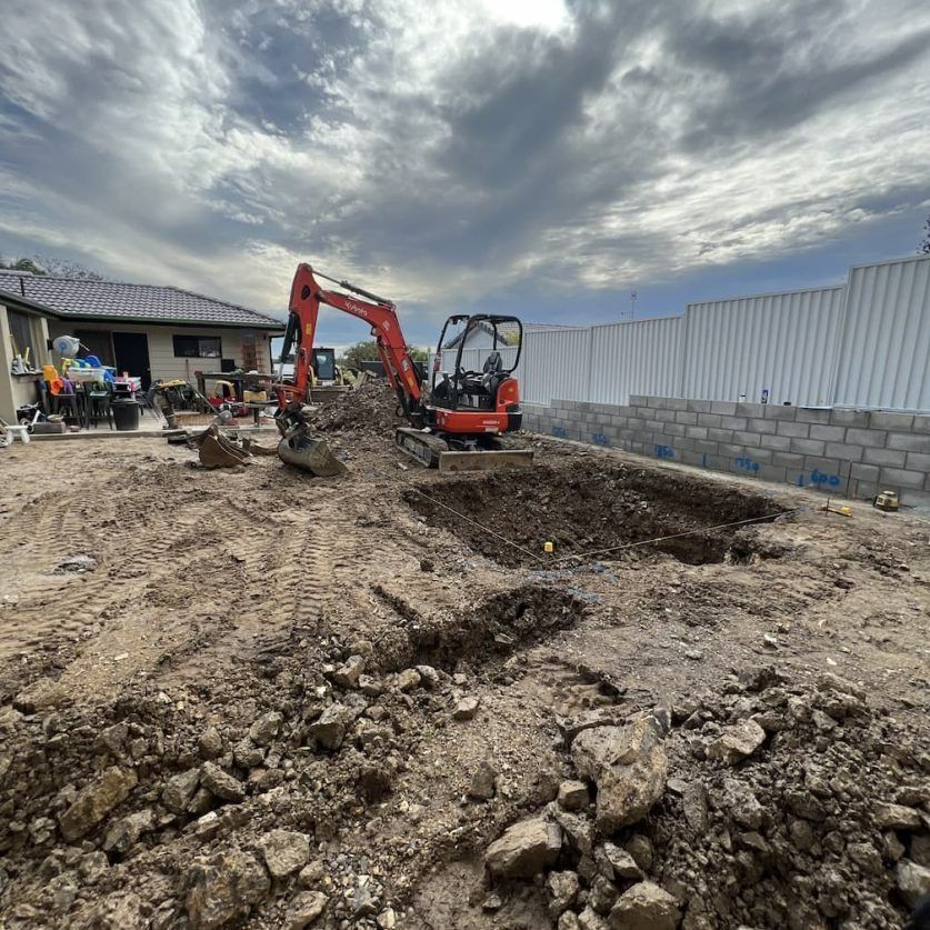 Mini Excavator Digging in a Residential Backyard, With a House and Fence — Bombs Away Pools in Coolangatta, QLD
