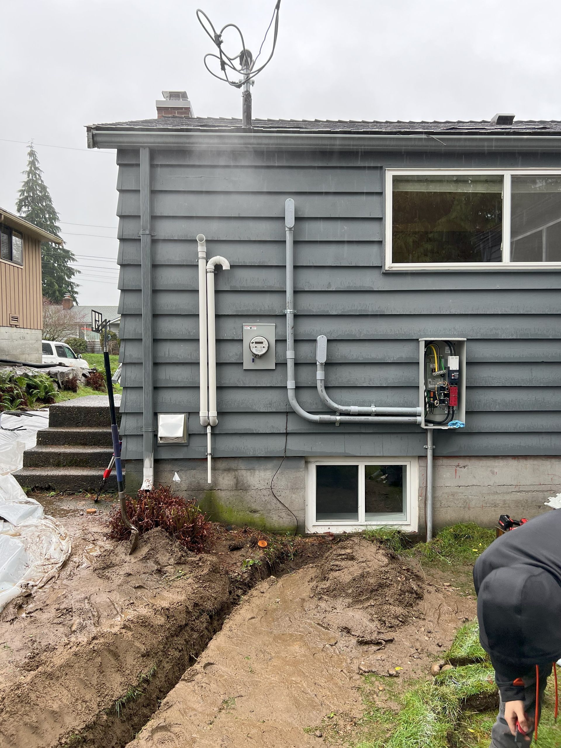 An electrician is digging a hole in front of a house working on new wiring