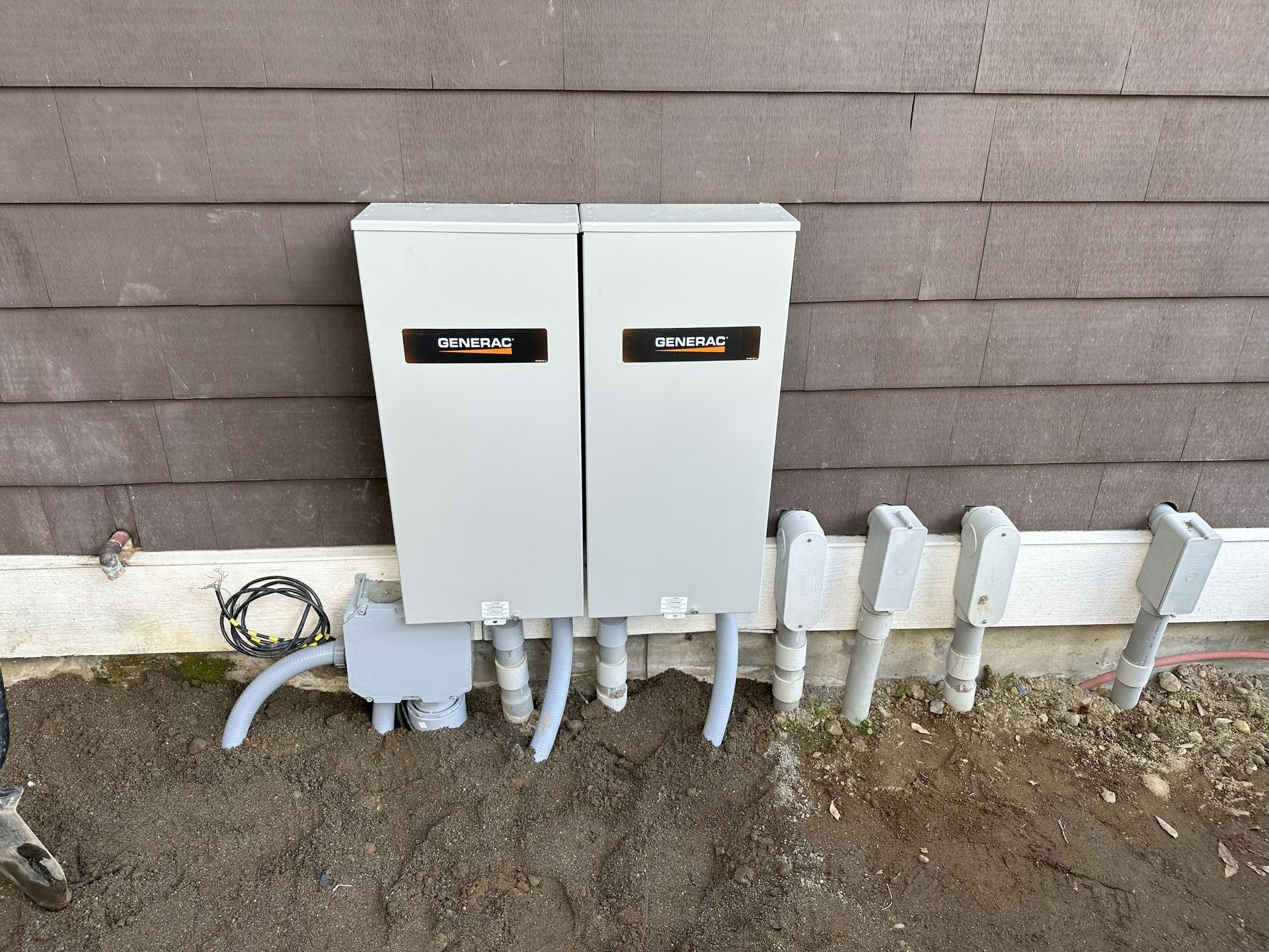 A couple of electrical boxes on the side of a building for a Generac generator.