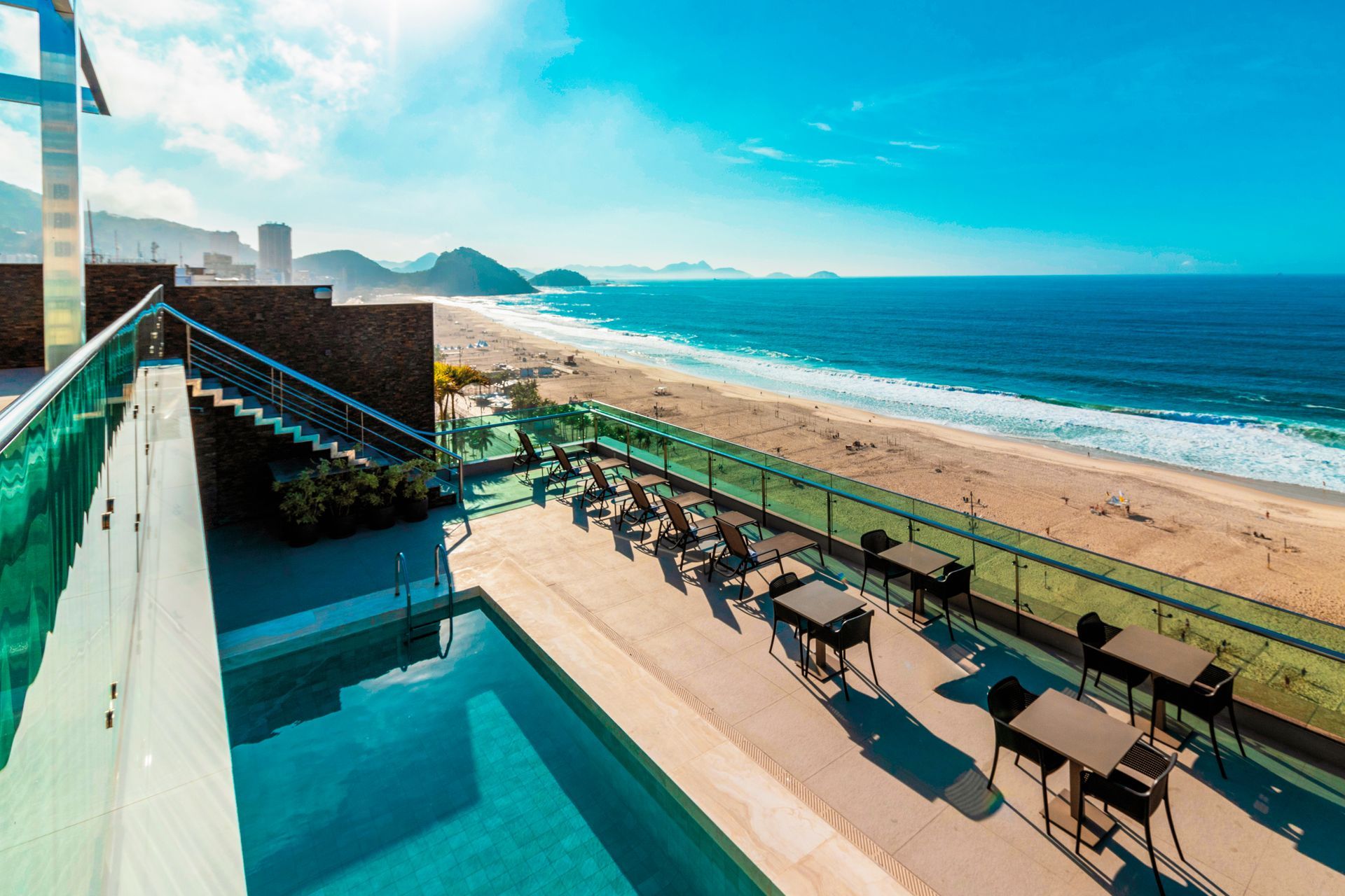 Um quarto de hotel moderno com uma cama bem arrumada, uma televisão fixada na parede, uma pequena escrivaninha e acesso ao banheiro.