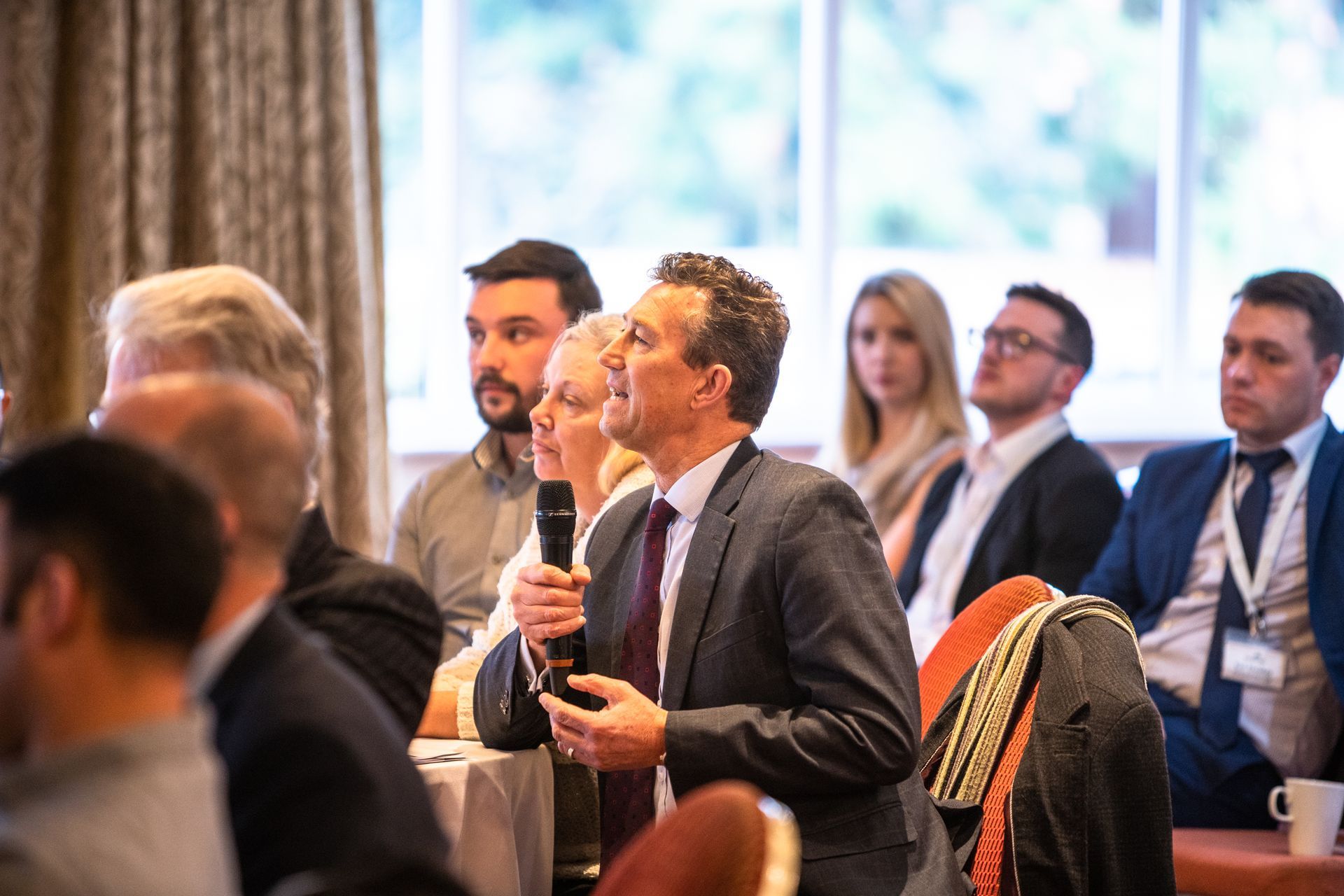 A group of people are sitting at tables at a conference.