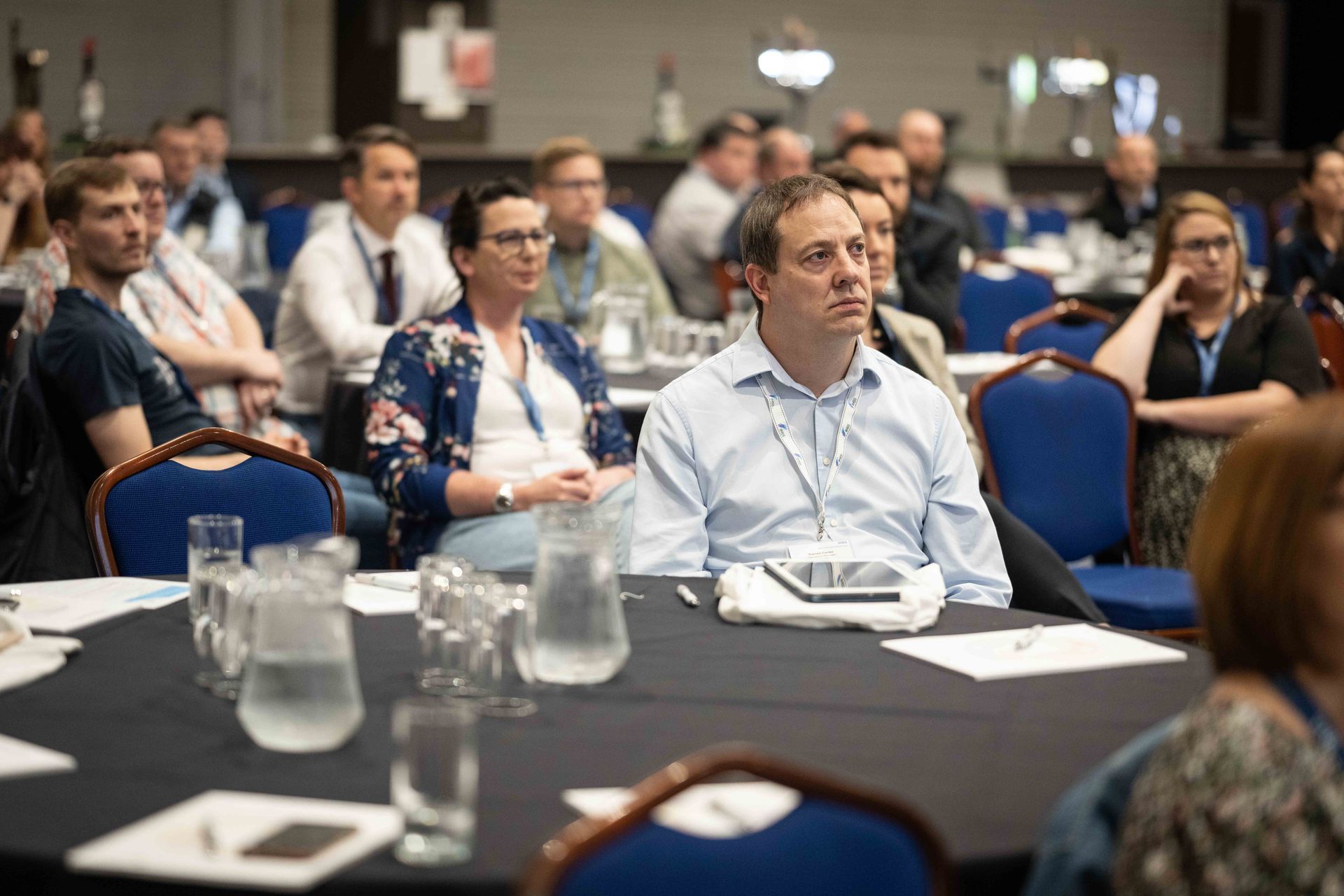 A group of people are sitting at tables at a conference.