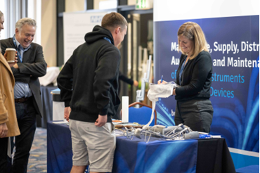 A group of people are standing around a table at a conference.