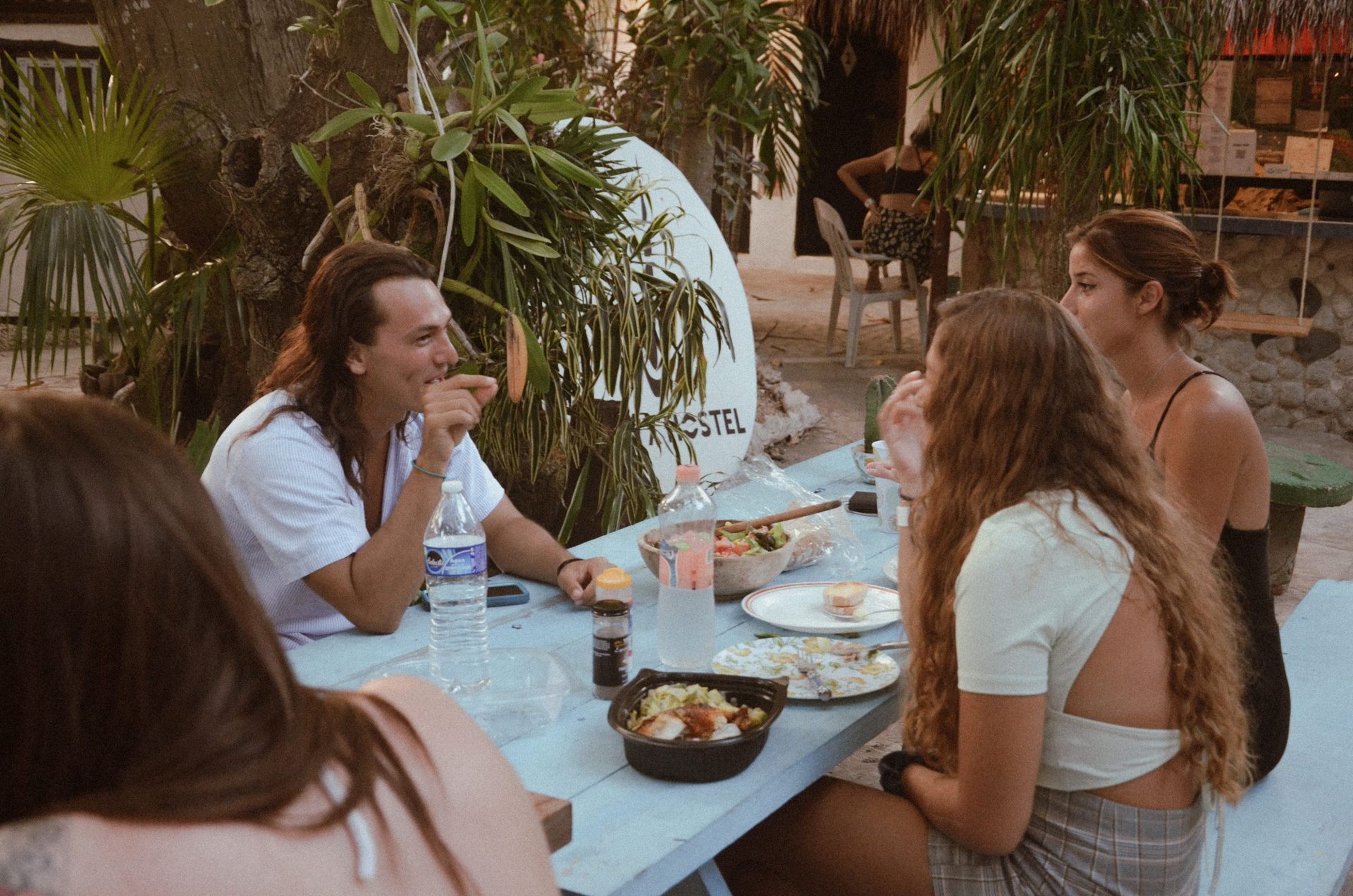 Grupo de personas sentadas en una mesa al aire libre, comiendo y conversando.