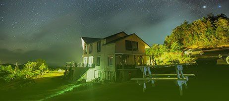 A house is lit up at night with a starry sky in the background.