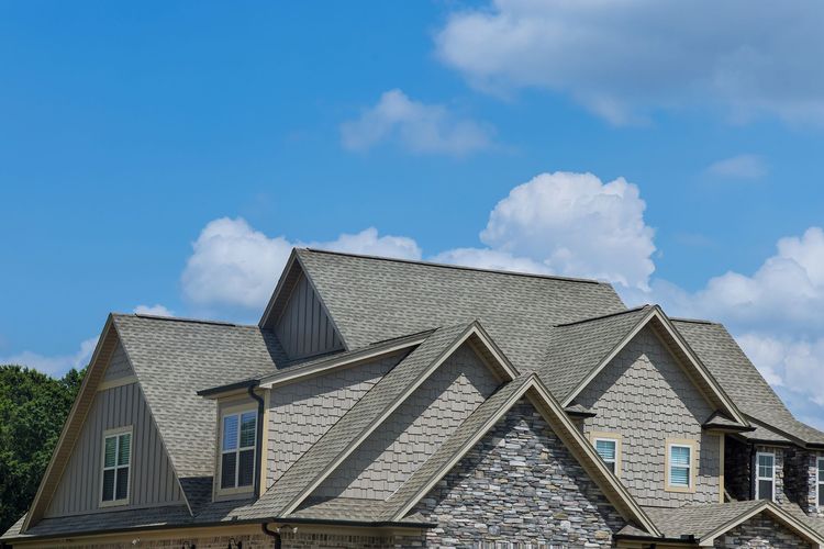 A large house with a gray roof and a blue sky in the background