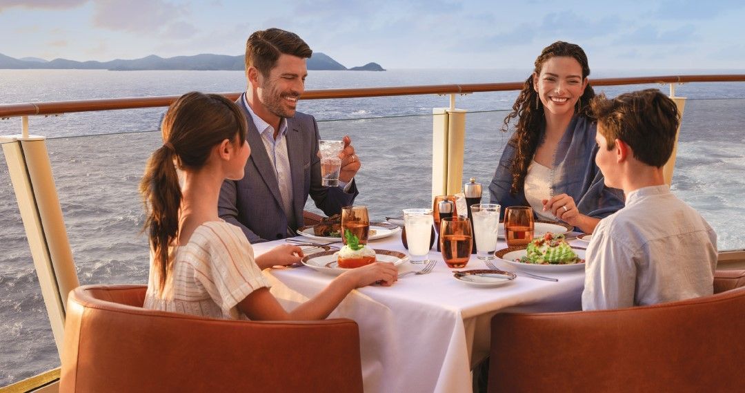 family having a dinner together on a cruise ship next to the ocean
