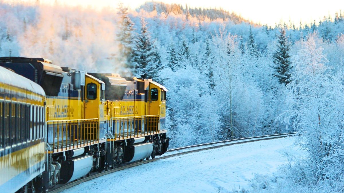 A train is going down the tracks in the snow.