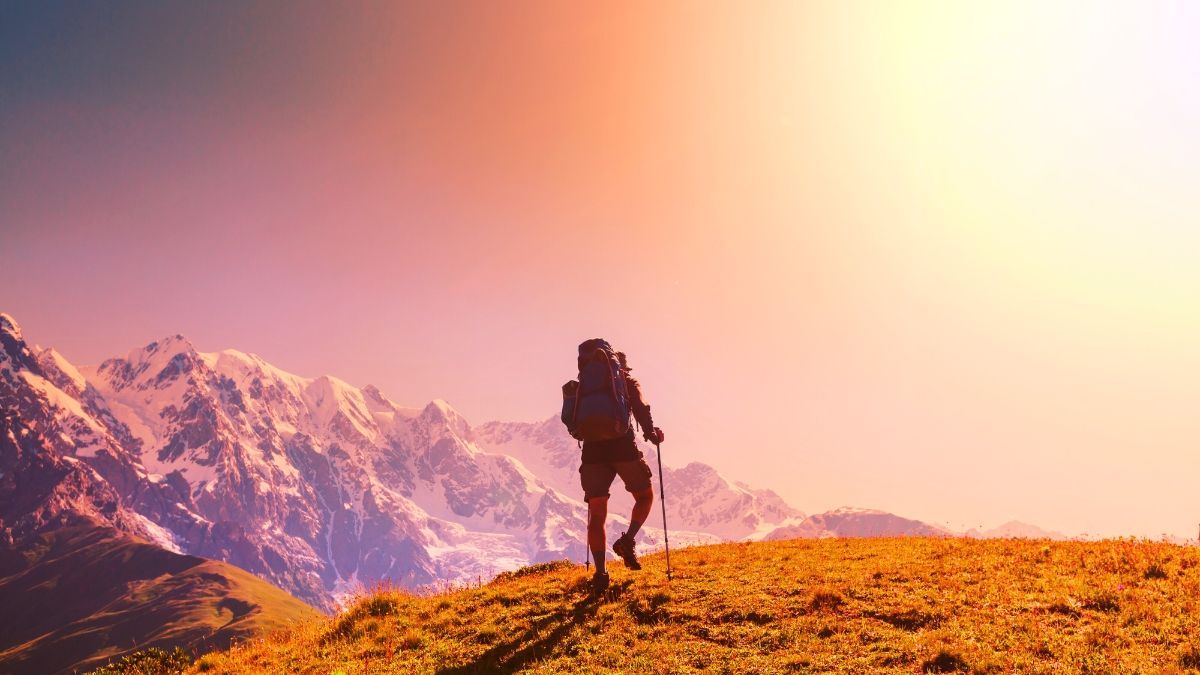 A person with a backpack is walking on top of a mountain.