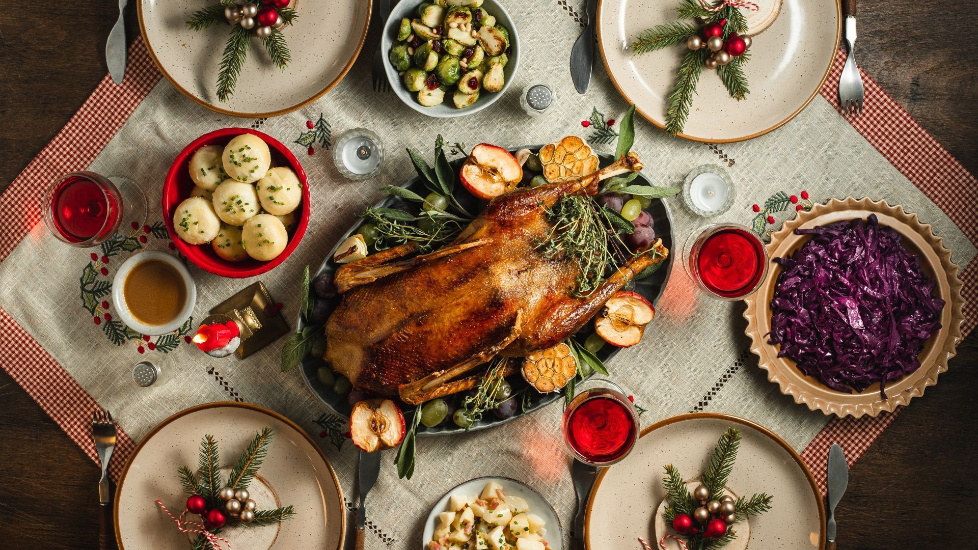 Festive table setting with roasted goose, side dishes, and place settings.
