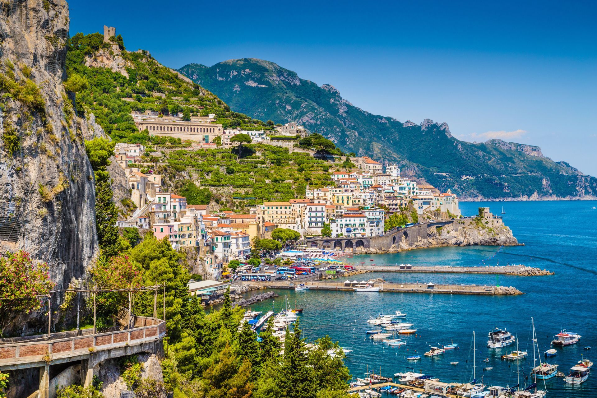 A small town on a hill overlooking the ocean with boats in the water.