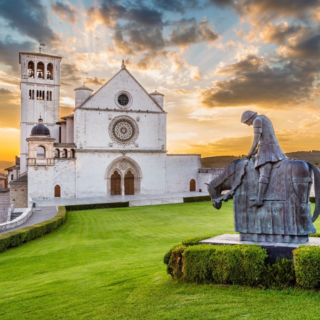 A statue of a man riding a horse in front of a the basilica of St Francis of Assisi
