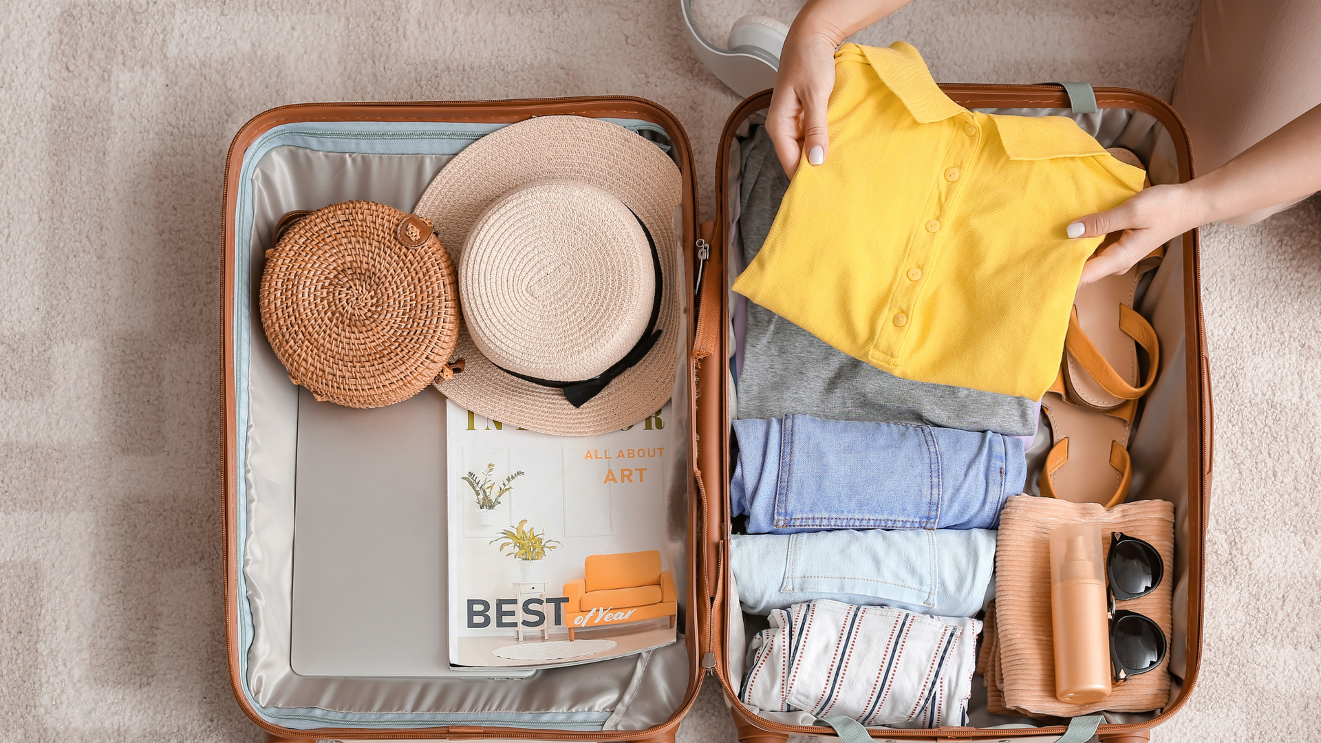 A person is packing a suitcase with clothes and a hat.