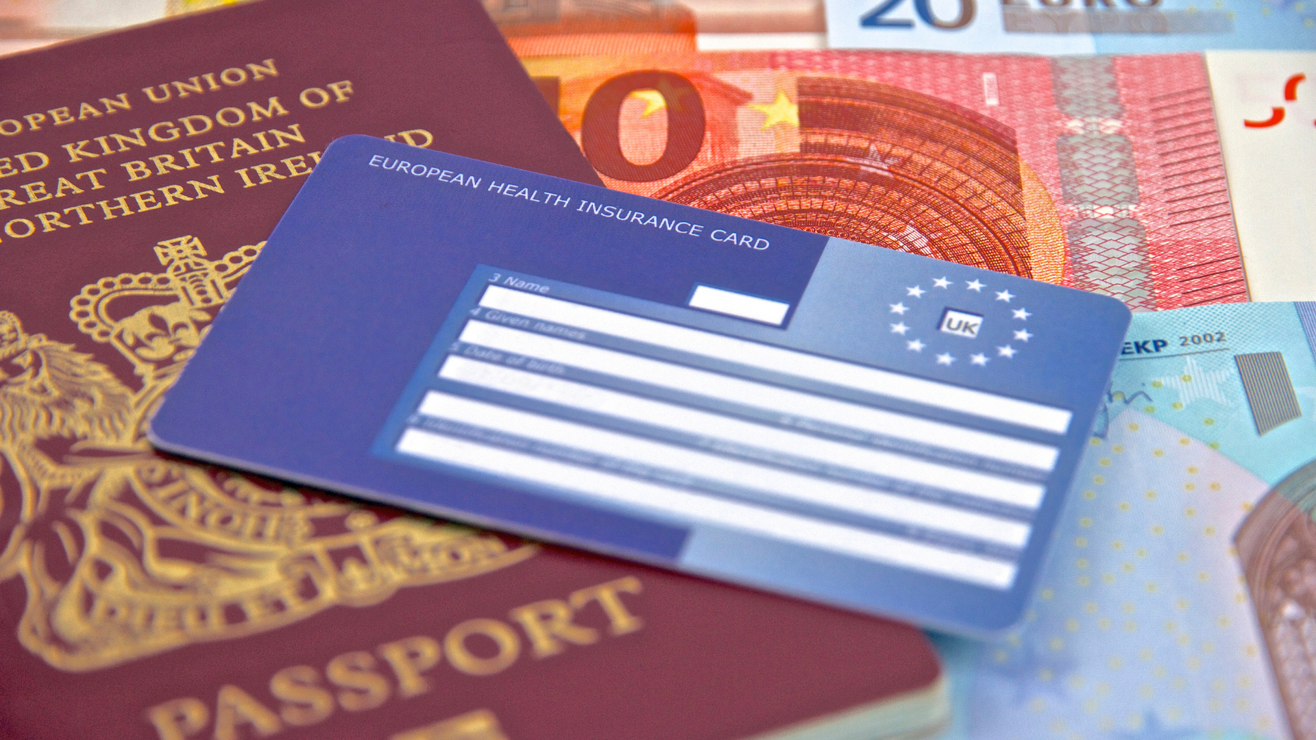 a passport and a European Helath Card are sitting on top of a pile of money .