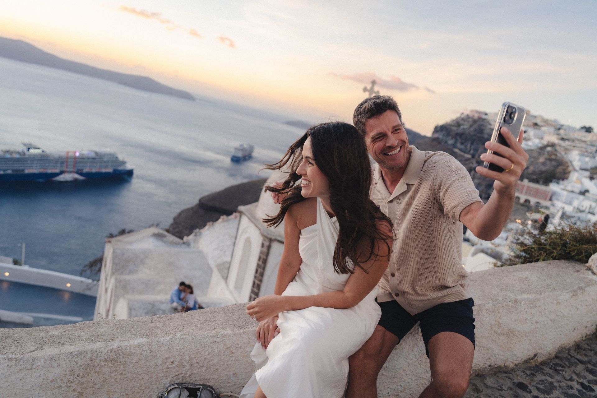 A man and a woman are sitting on a wall taking a selfie.