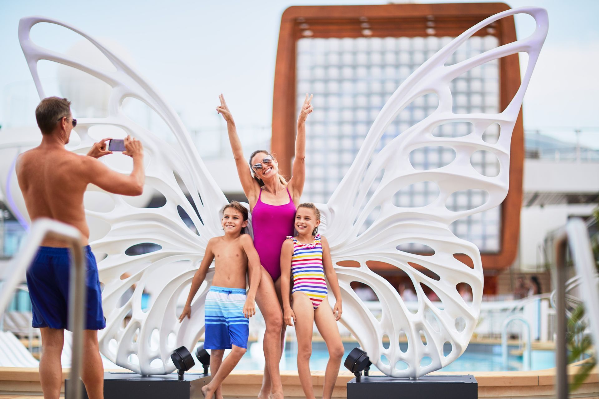 A family is posing for a picture in front of a butterfly sculpture.