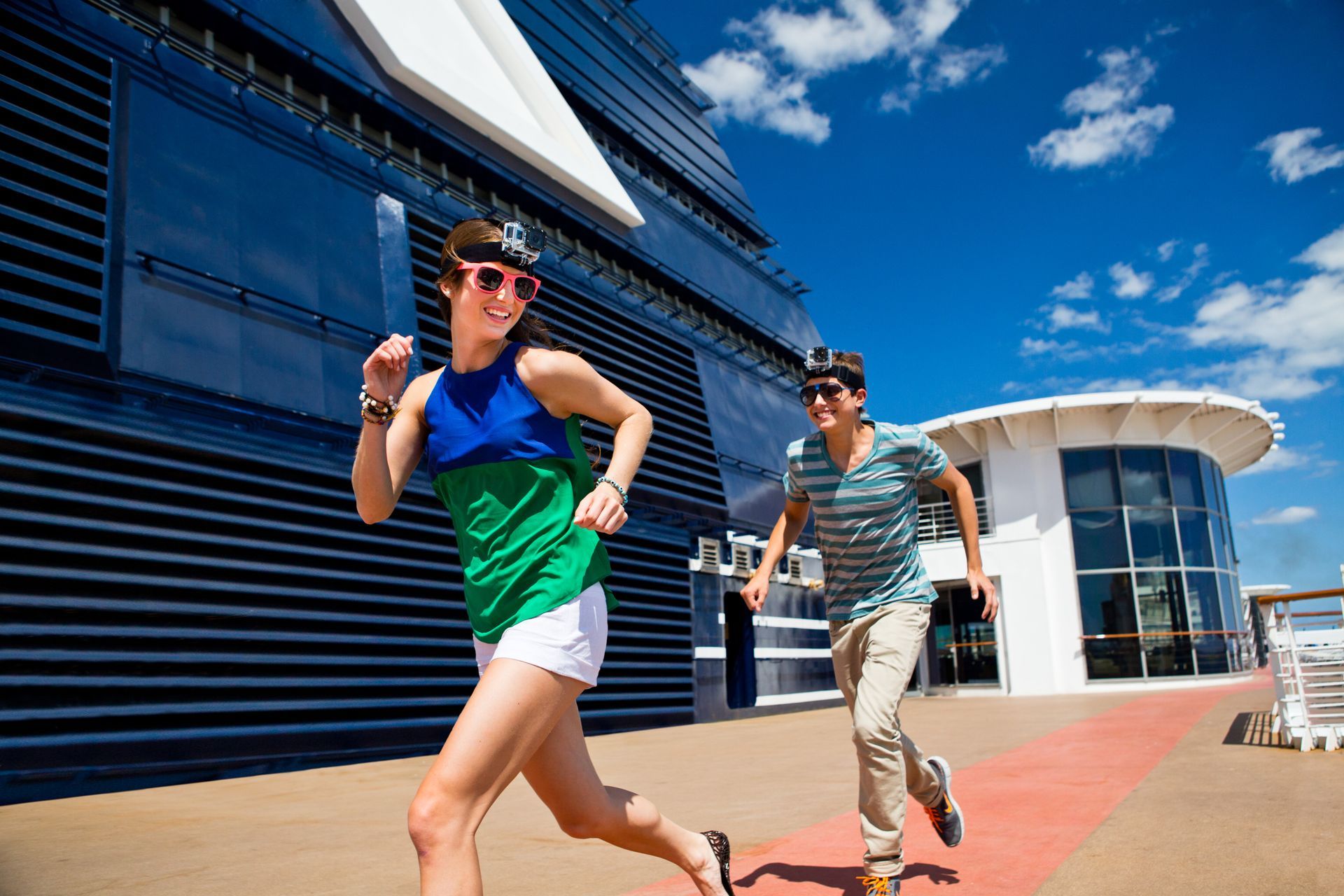 A man and a woman are running in front of a cruise ship.