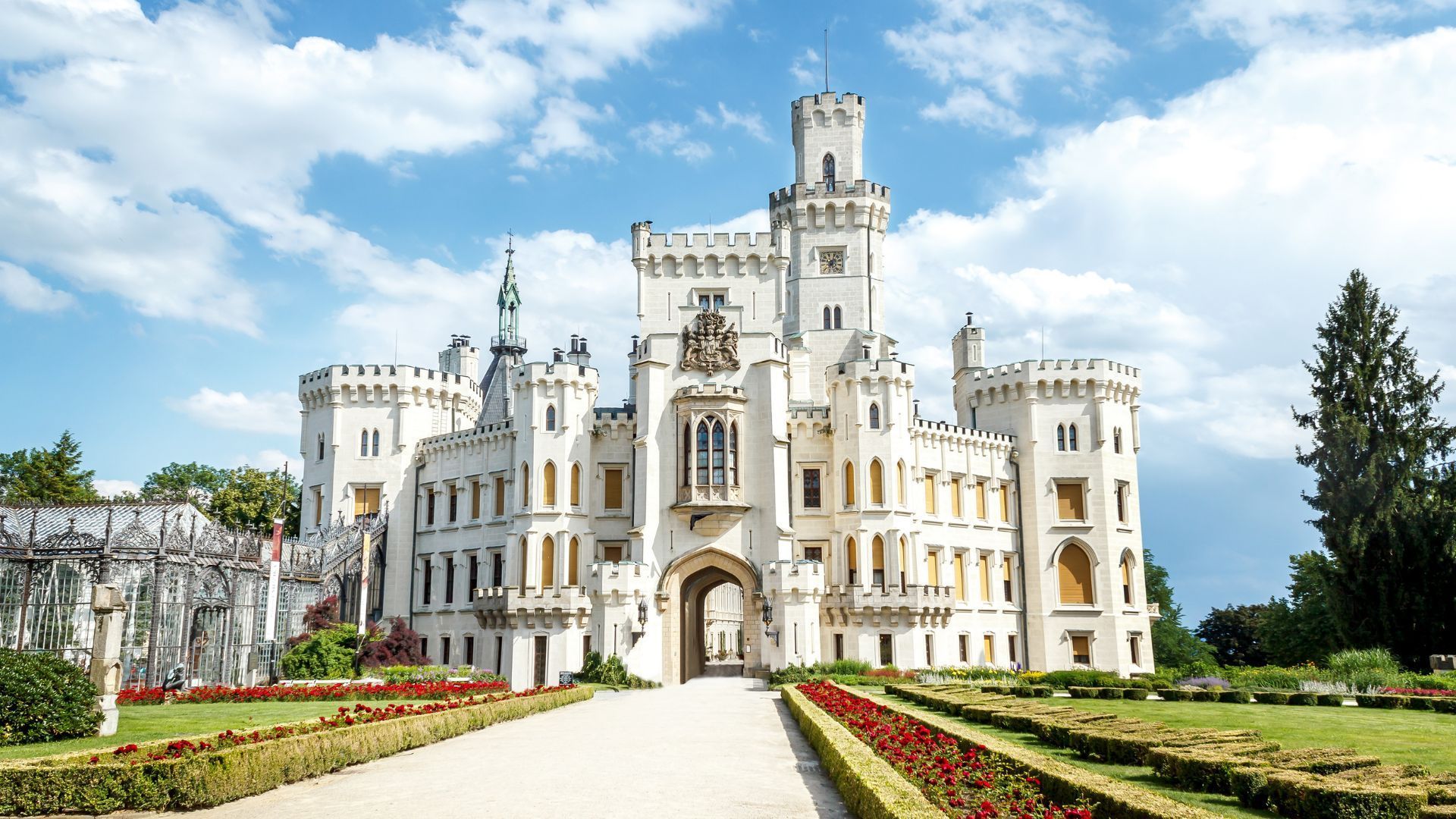 White Hluboká Castle in the Czech Republic with towers and archway, on a sunny day.