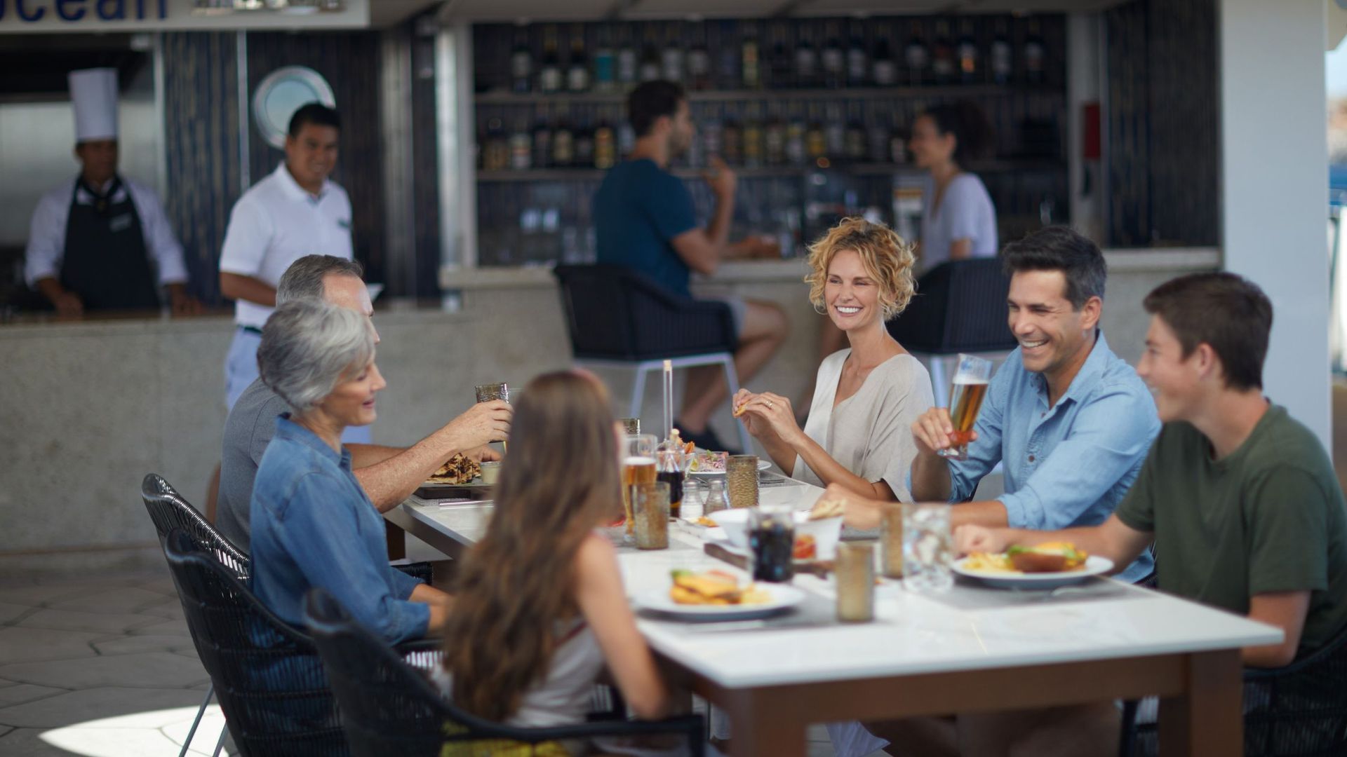 A group of people are sitting at a table in a restaurant onboard celebrity cruise.