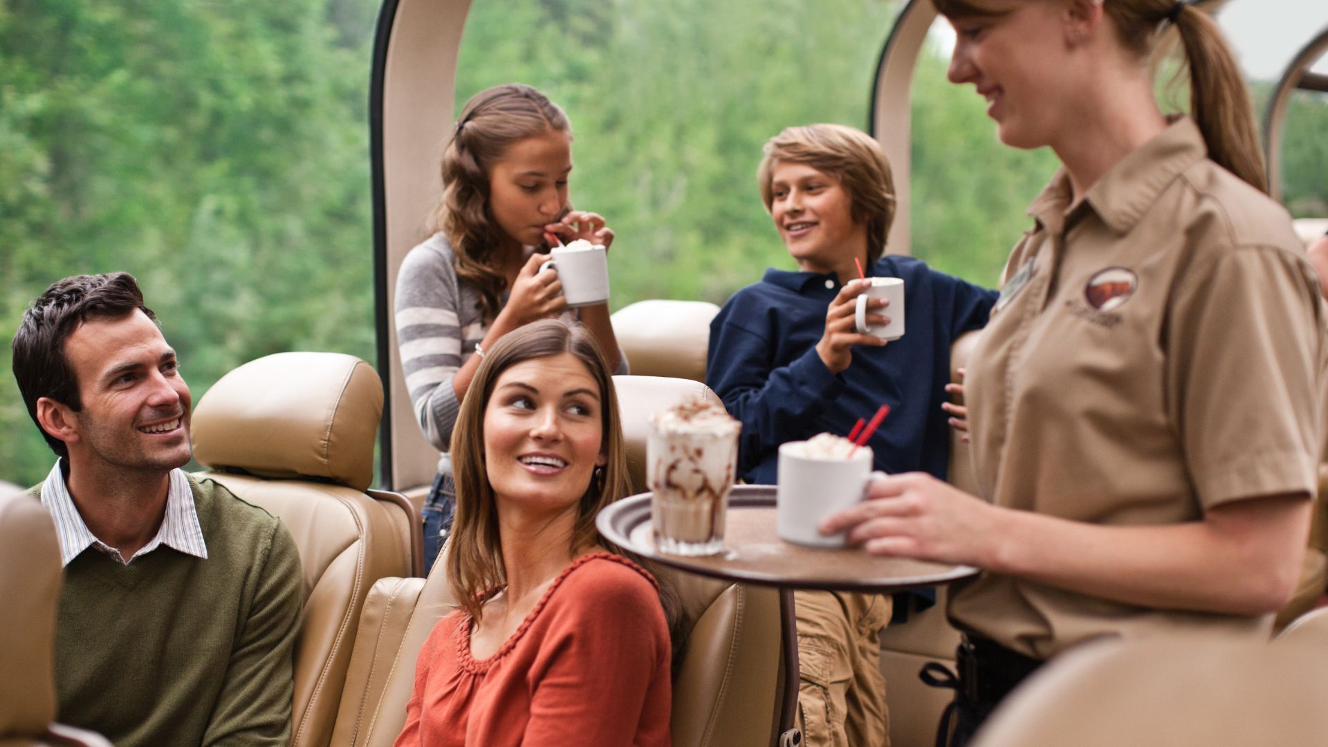 A woman is serving drinks to a group of people on a train.