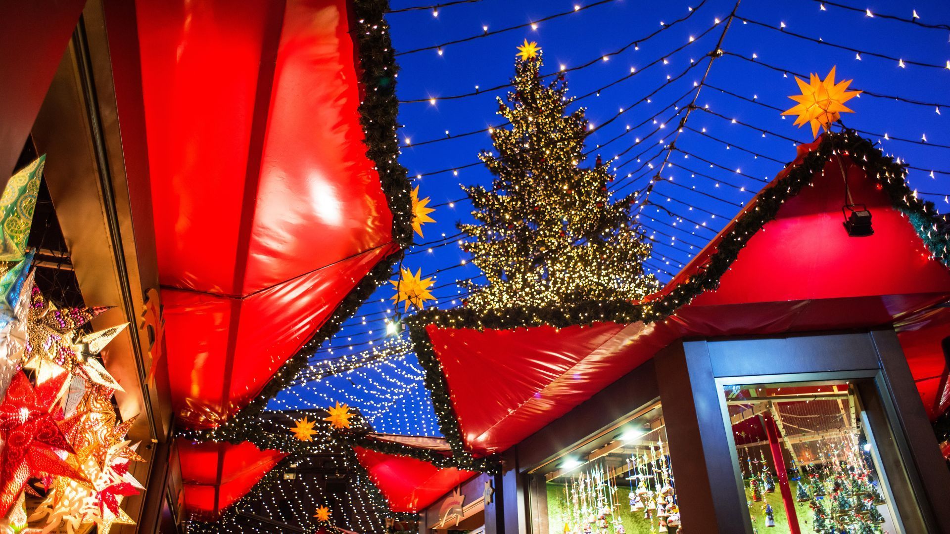 A christmas market with a christmas tree in the background.