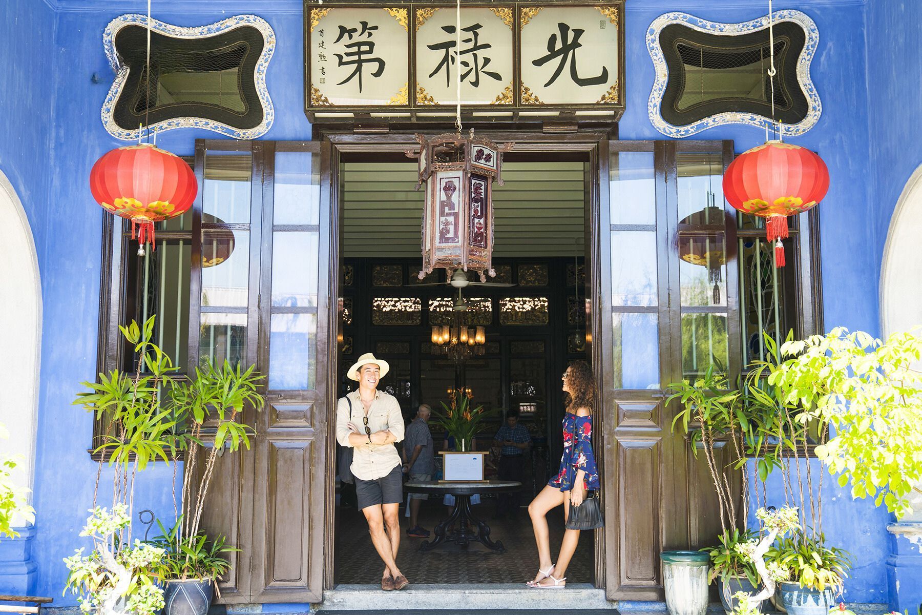 Contiki Asia A man and a woman standing in front of a blue building with chinese writing on it Barters Travelnet