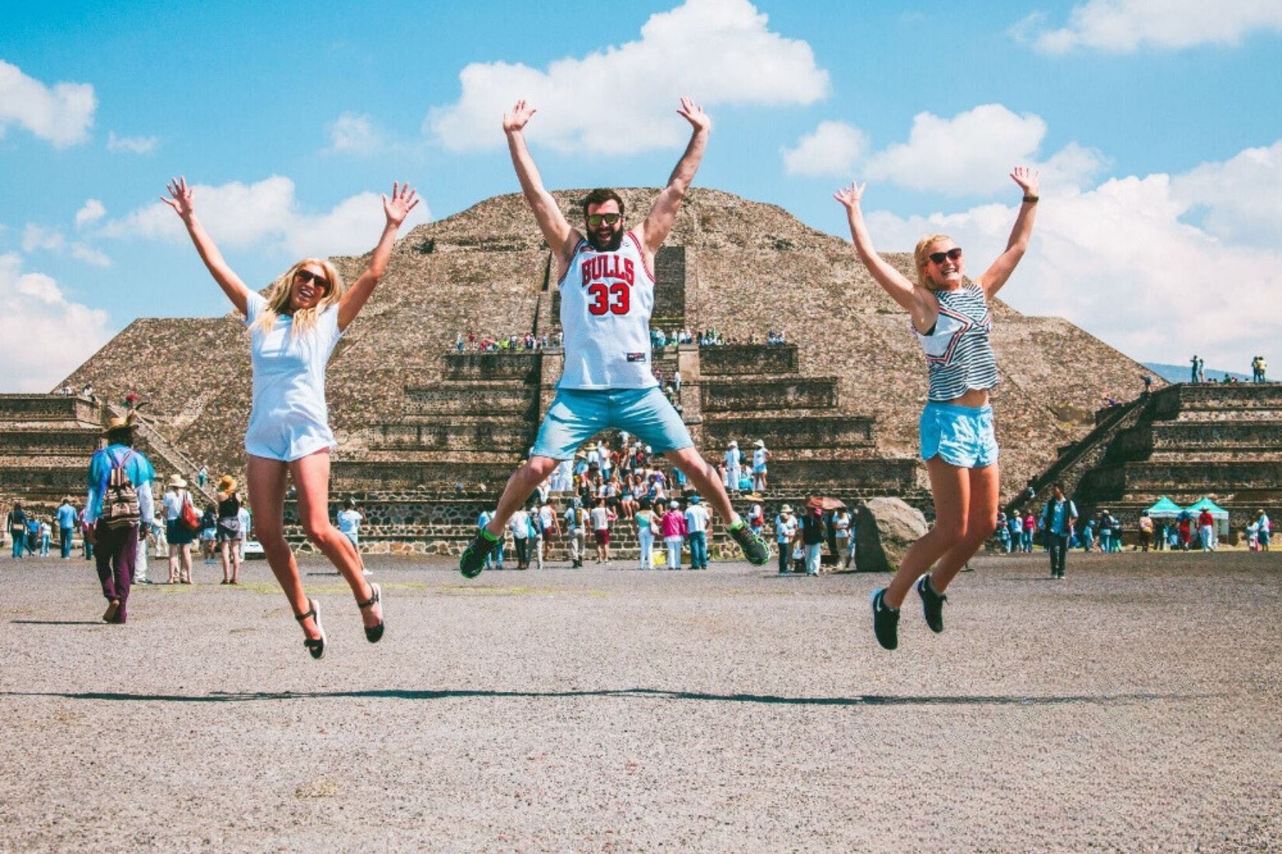 Contiki Latin America A group of people are jumping in the air in front of a pyramid Barters Travelnet