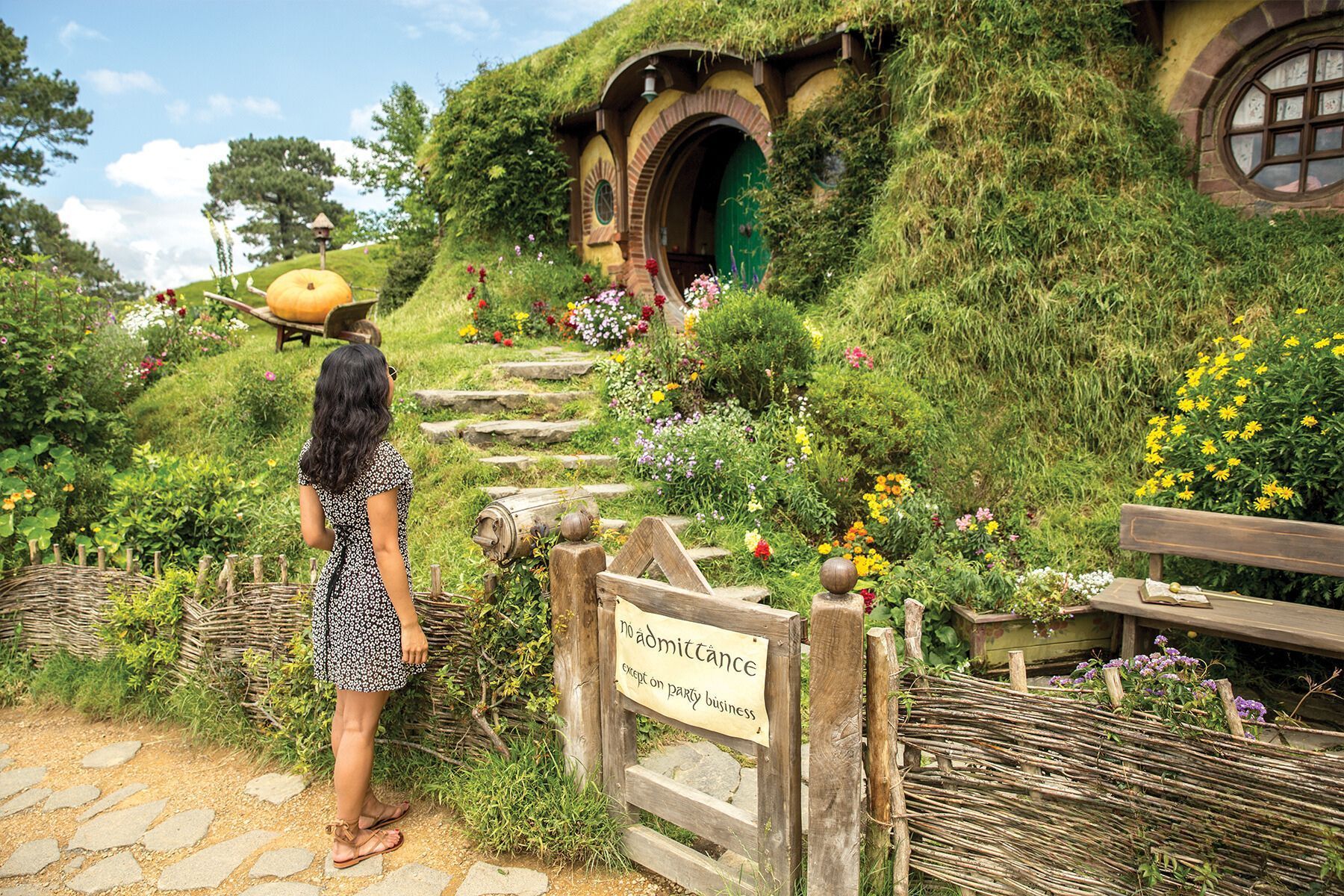 Contiki New Zealand A woman is standing in front of a hobbit house Barters Travelnet