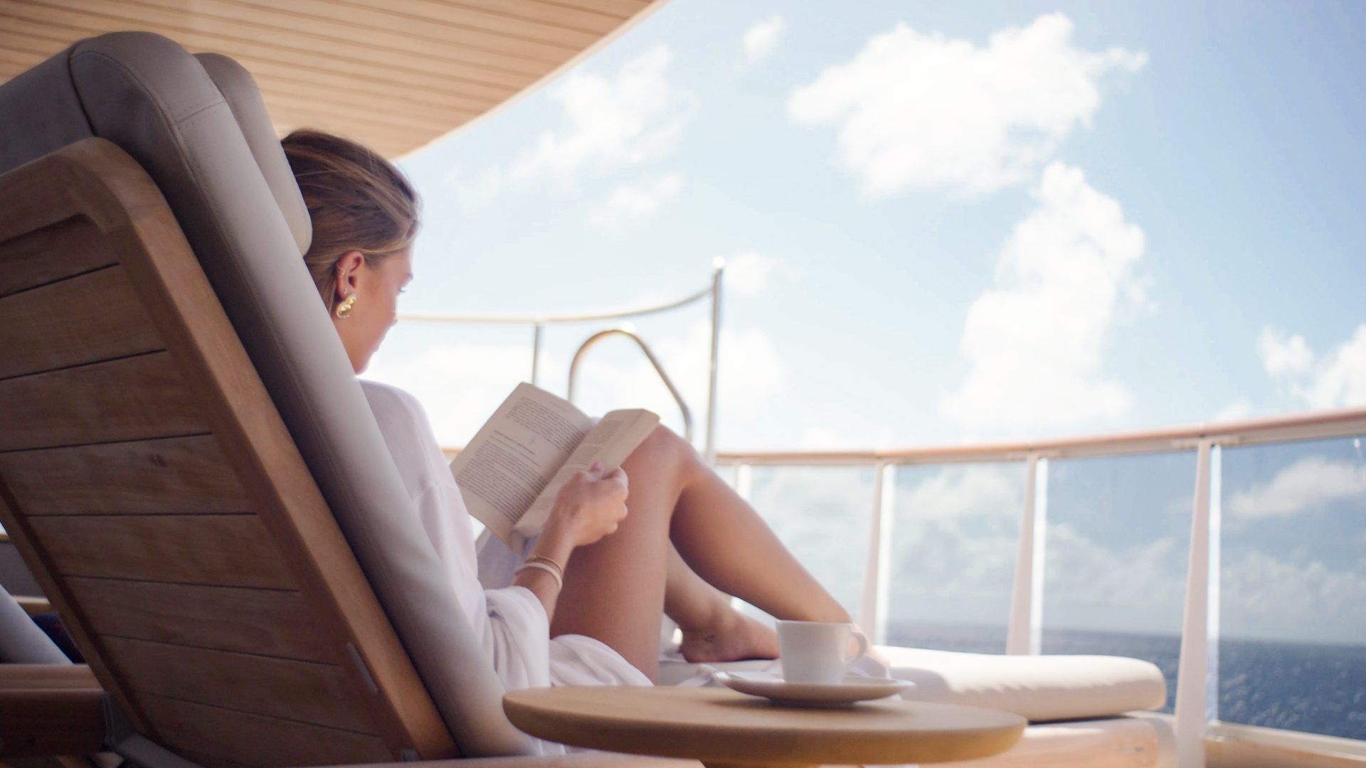 A woman reading a book on a lounge Explora Journeys Barters Travelent