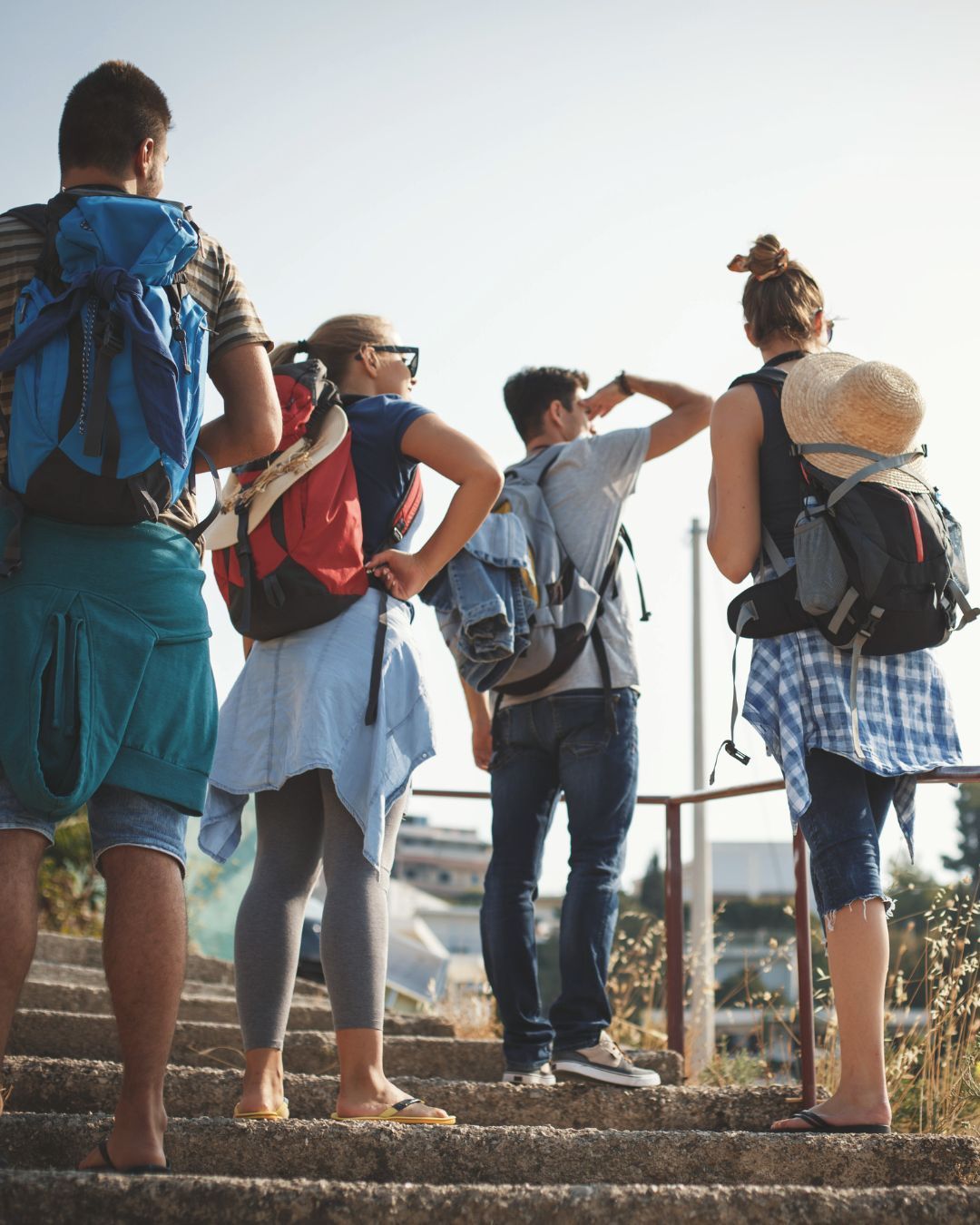 Backpackers standing on a trail, looking out over a sunlit landscape.