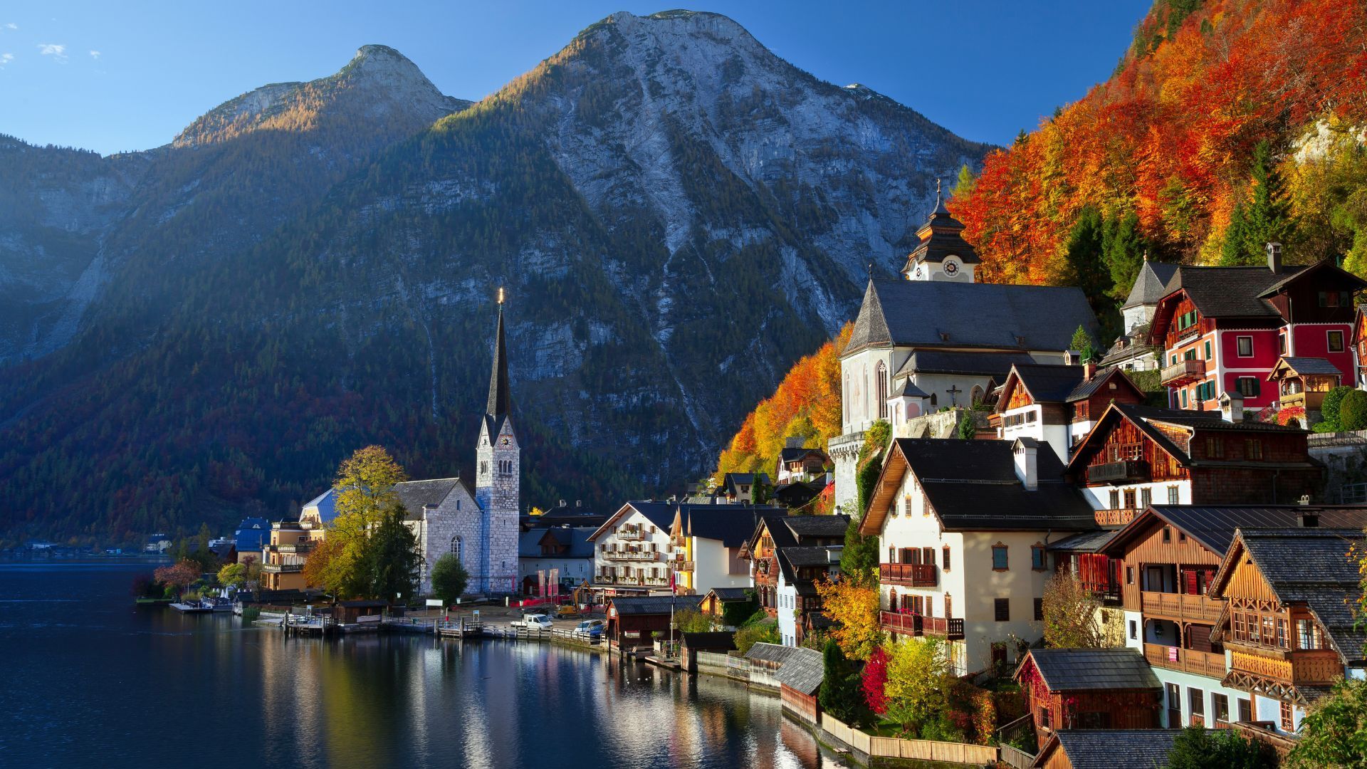 Hallstatt, Austria: Lakeside village with colorful buildings, church, and mountain backdrop. Autumn foliage.