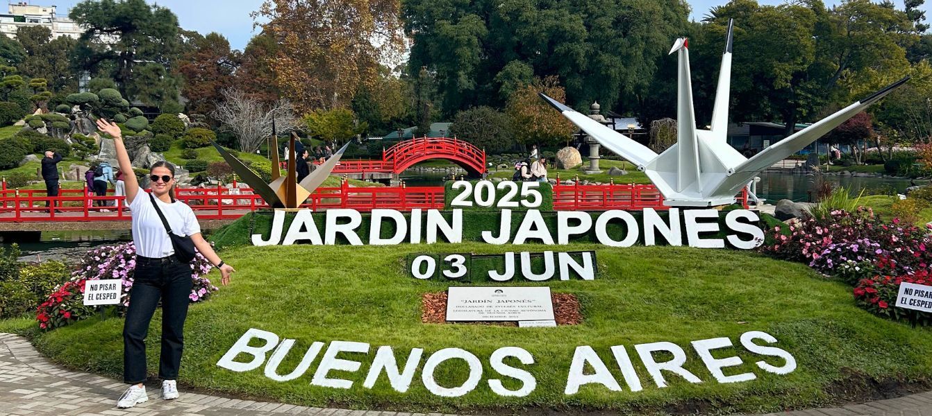 A woman is standing in front of a sign that says jardin japones.